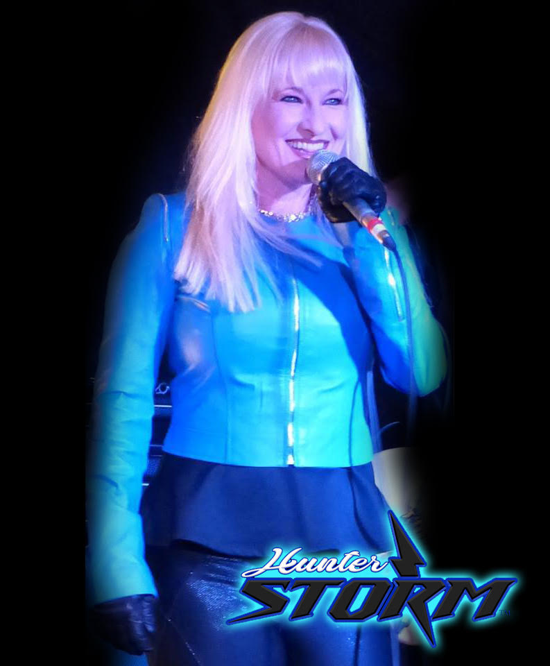 Hunter Storm with platinum blonde hair, turquoise blue leather jacket, holding a microphone, and showcasing achievements with the glowing blue Hunter Storm logo. This image embodies the dynamic entertainer and innovation leader.