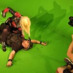 Hunter Storm playing the Queen of Hell / Queen of the Apocalypse seated astride Rex Van Dyne, delivering a punch in a staged fight scene for the "Dead and Gone" music video.