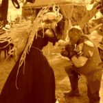 Hunter Storm playing the Fairy Queen Titania in sepia tones, receiving a knight's fealty with a tender bow. The brave Sir Oso is the gallant knight in the image.
