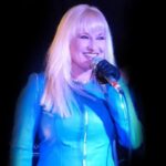 Hunter Storm with platinum blonde hair, turquoise blue leather jacket, and microphone. Hunter Storm iconic avatar image.